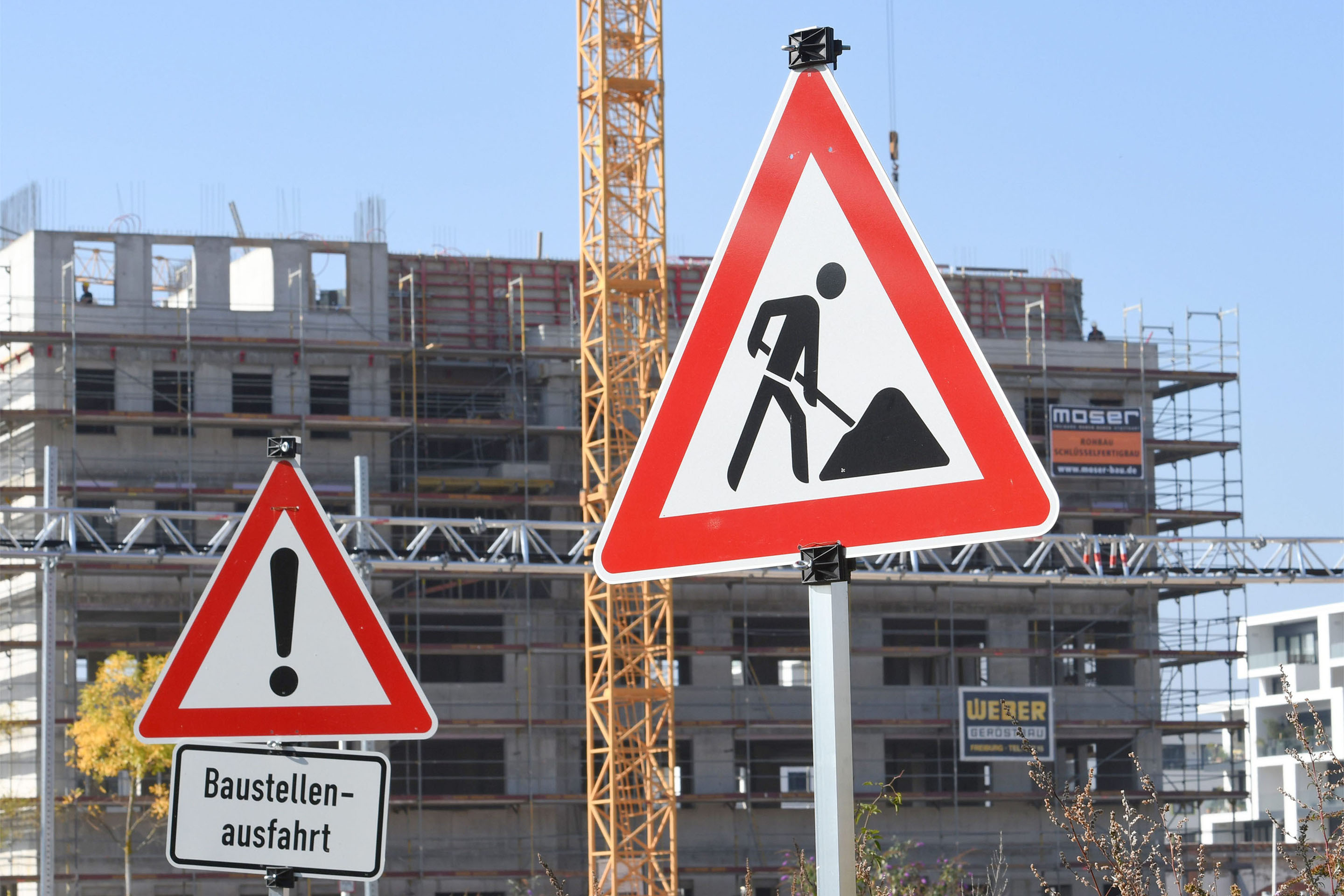 Warnschilder: Baustelle und Baustellenausfahrtin einem Neubauviertel in Freiburg. Überall in Deutschland mangelt es an bezahlbarem Wohnraum - Wohnungsgemeinnützigkeit 