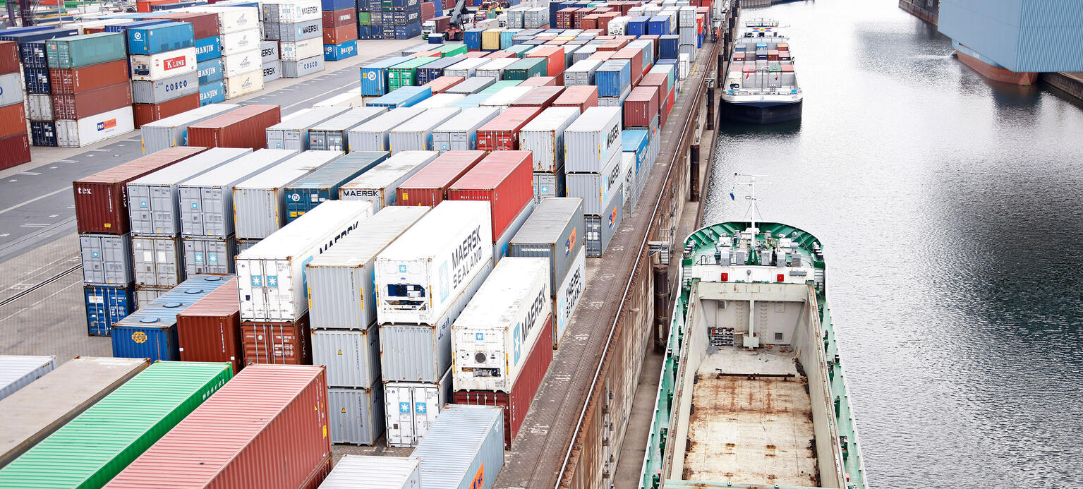 Containerverladung in einem Containerhafen. Es ankert ein leeres Containerschiff.